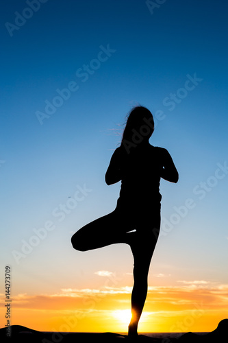 Shadow of a girl who does yoga on the beach at sunset time. San Diego. California