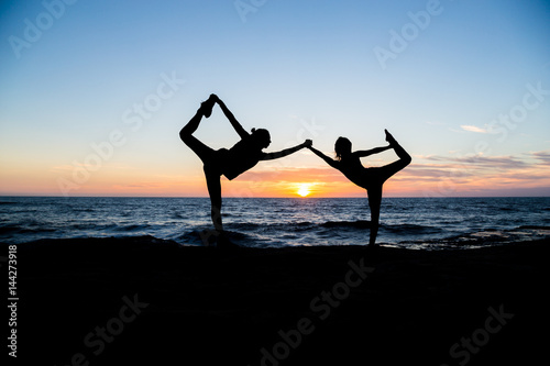 Two girls doing yoga on the beach at sunset time. San Diego. California. Yoga poses