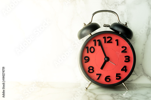 Red alarm clock on marble sureface counting at 7 photo