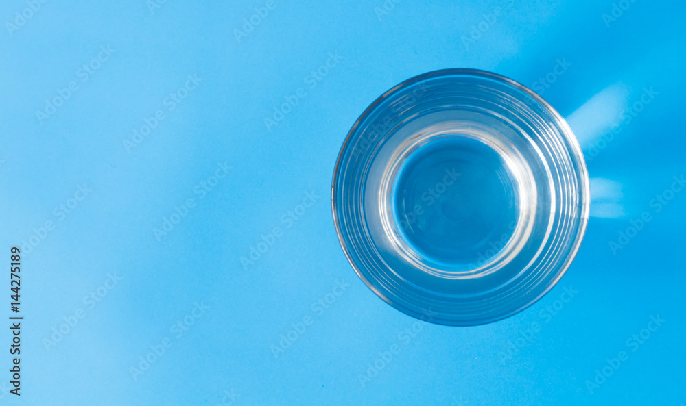 Closeup top view water in glass on blue background