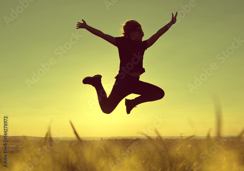 Young happiness woman jumping high at sunset.
