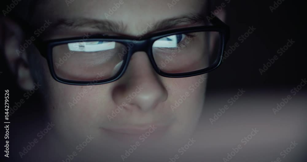 boy working at a computer in a dark room, surfing the Internet, close-up boy working at a computer in a dark room, surfing the Internet, close-up