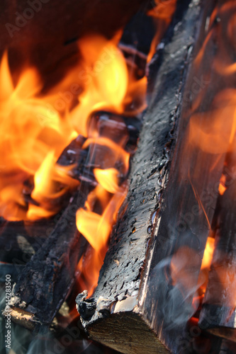 Charred wood and bright flames on dark background