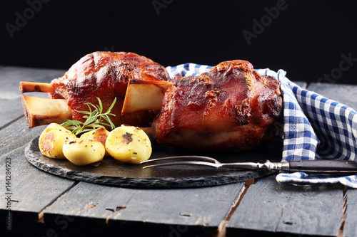 Canvas Print Smoked ham hock with herbs and spices on wooden plate.