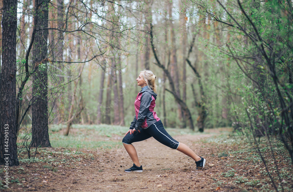 young beautiful girl doing workout in the woods. Blonde girl tracksuit doing exercises young beautiful girl doing workout in the woods. Blonde girl tracksuit doing exercises