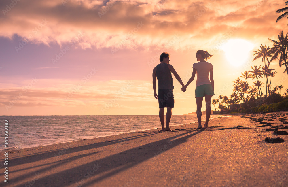 Man and woman walking on the beach holding hands. 