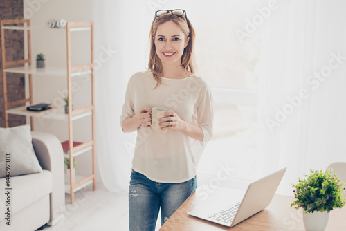 Horizontal portrait of young pretty employee drinking coffee and having break at work photo