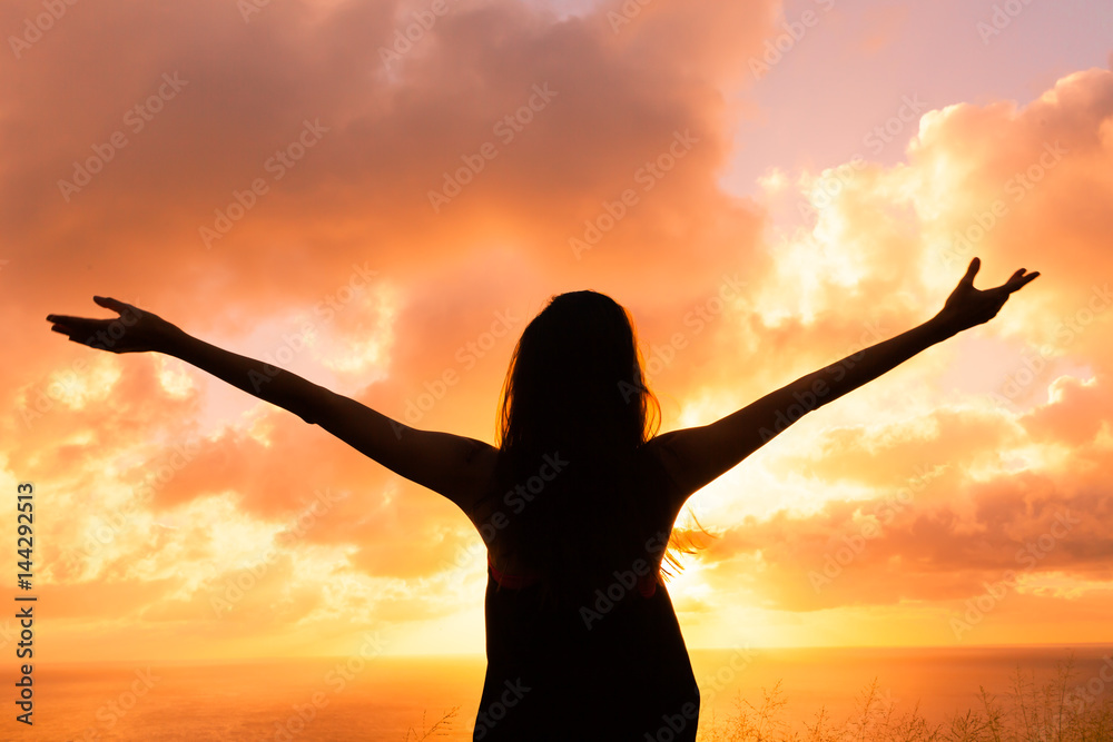 Happy and free woman enjoying the beautiful sunset.