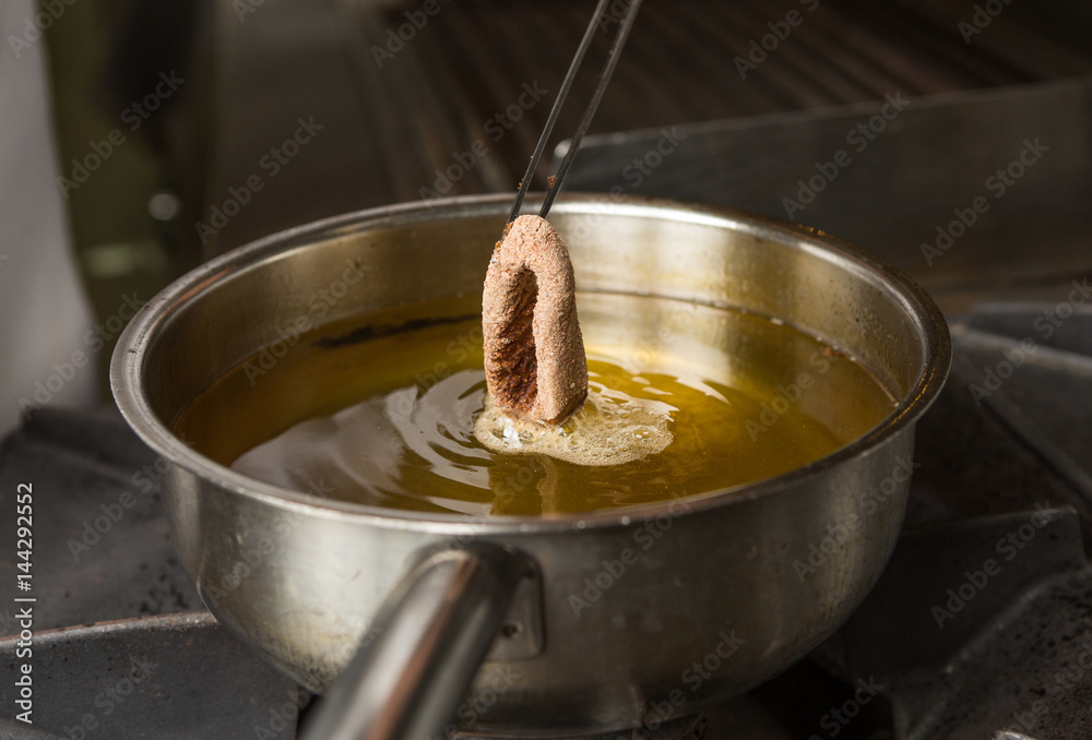 Calamari ring being placed into a pan of hot oil. Calamari ring being placed into a pan of hot oil.