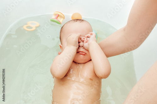 infant baby girl having bath with mother help