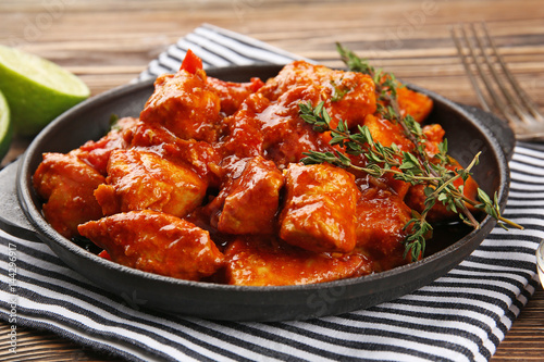 Foto Frying pan with delicious chicken tikka masala on napkin
