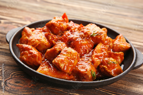 Tableau sur toile Frying pan with delicious chicken tikka masala on wooden table