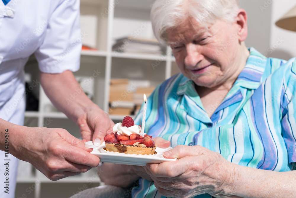 Senior woman receiving a little birthday cake from her nurse Senior woman receiving a little birthday cake from her nurse