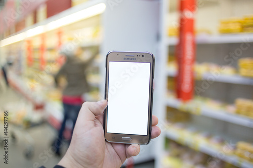 hand holding mobile smart phone on Supermarket blur background, business concept