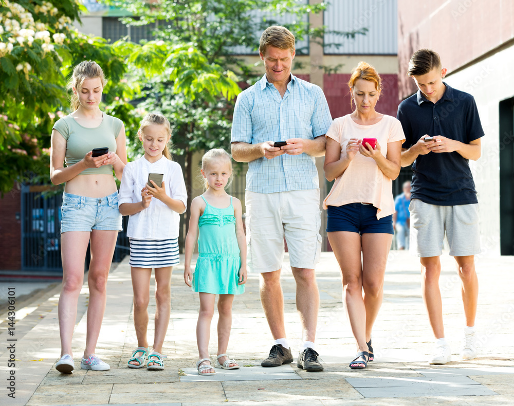 Fototapeta premium Young family with children looking at phone