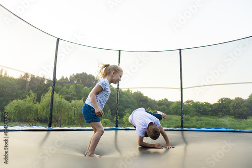 Children jumping on a trampoline in a park without parental supervision photo