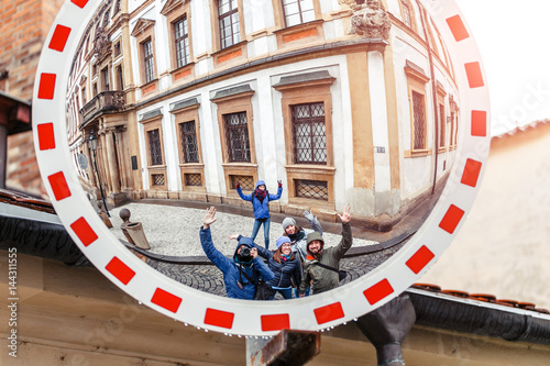 Group of friends having fun with their reflection in a convex security road mirror.