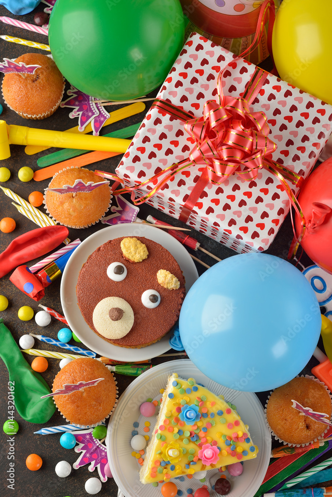 Birthday cake and various accessories for the holiday on a brown background