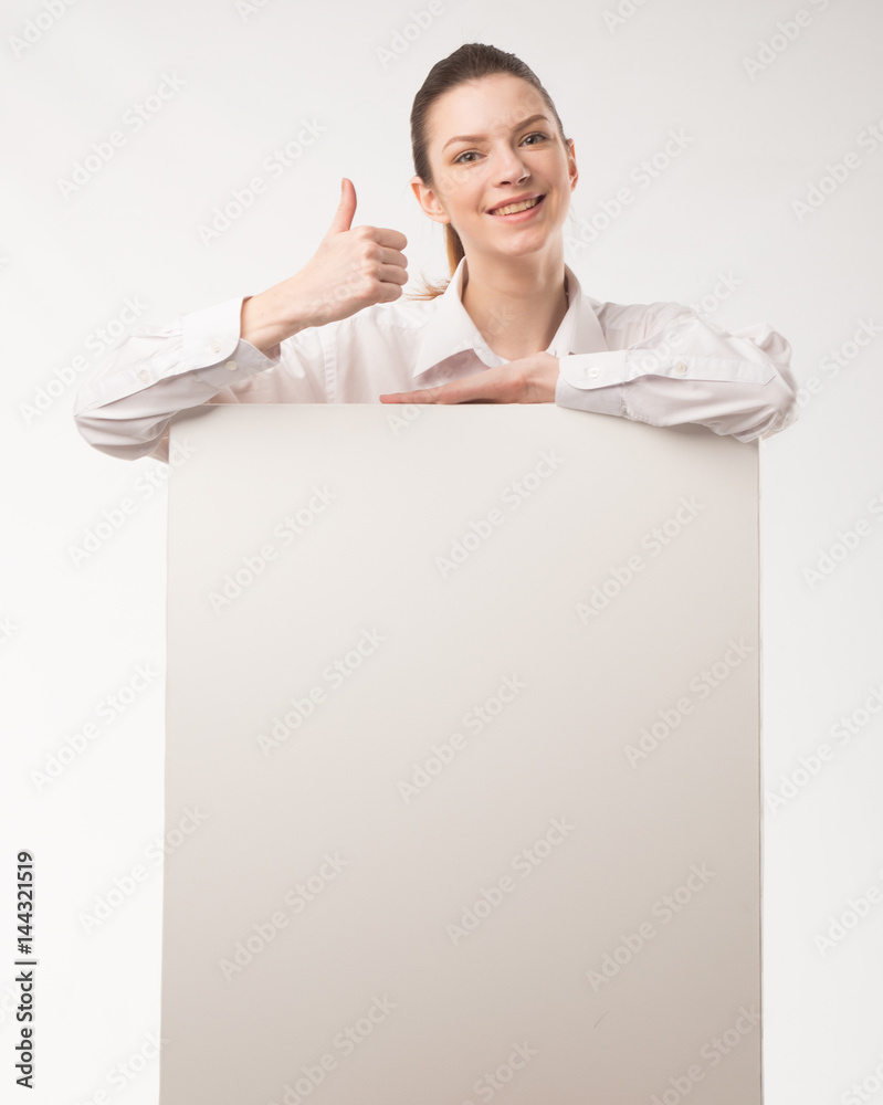 Young happy woman showing presentation, pointing on placard over gray background Young happy woman showing presentation, pointing on placard over gray background