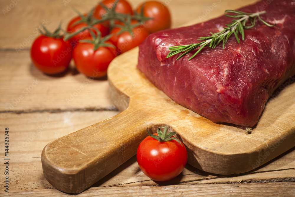 Raw beef steak on a cutting board with rosemary and spices. Raw beef steak on a cutting board with rosemary and spices.