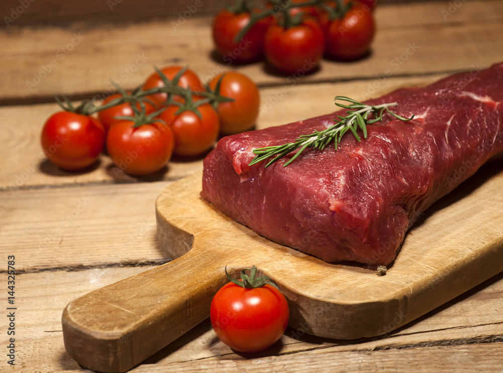 Raw beef steak on a cutting board with rosemary and spices. Raw beef steak on a cutting board with rosemary and spices.