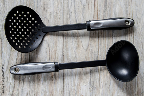 black ladle and skimmer on wooden background