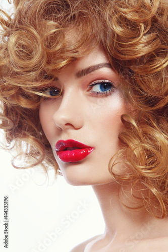 Young beautiful blue-eyed woman with curly hair and red lipstick