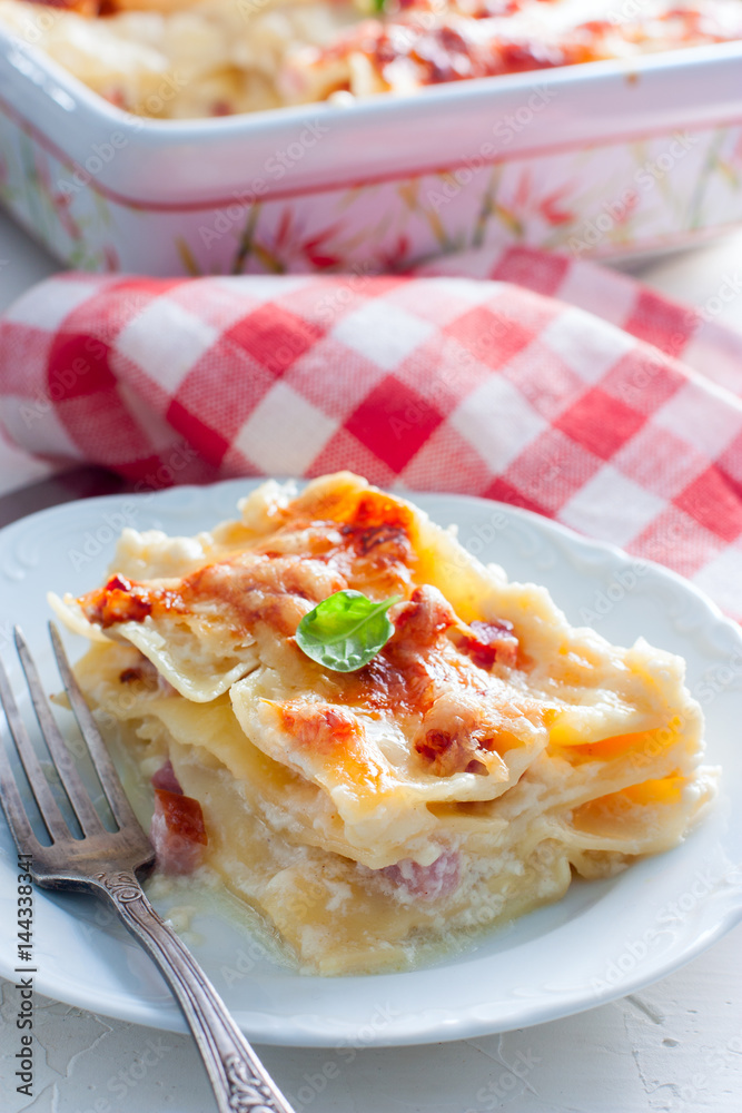 Cut a piece of lasagna with ham, selective focus