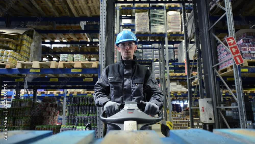 Caucasian Pallet Lifter Operator in the Warehouse. Storage and Wholesale Industry