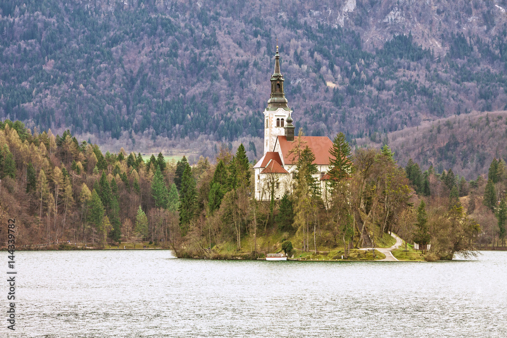 Slovenia - Bled - Lake Bled, Bled island and church of Assumption of Mary with blurred surrounding mountains covered by forest