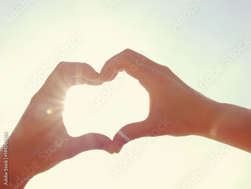 Female hands in the form of heart against the sky. Hands in shape of love heart