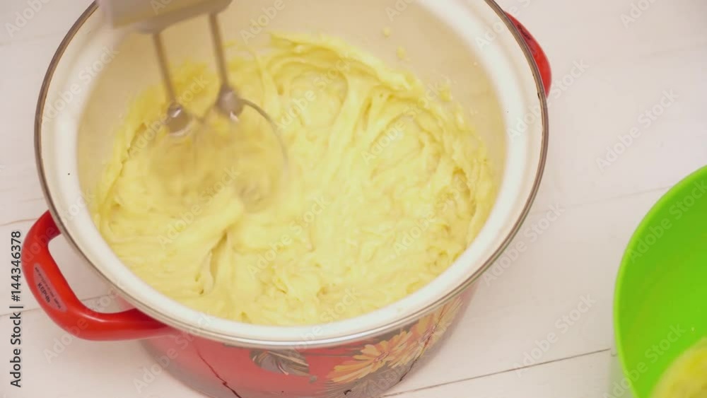 Woman stirring the dough and adding stirred eggs to it Woman stirring the dough and adding stirred eggs to it
