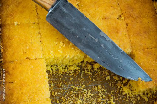 A knife sits atop a pan of cornbread at a country home. photo