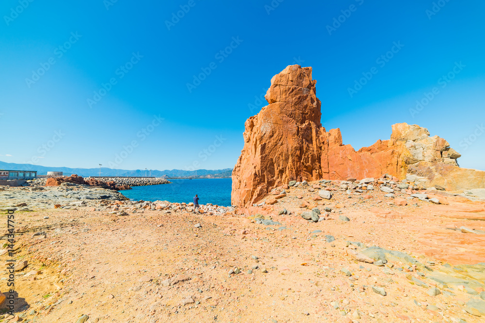 Man by a huge rock in Rocce Rosse beach