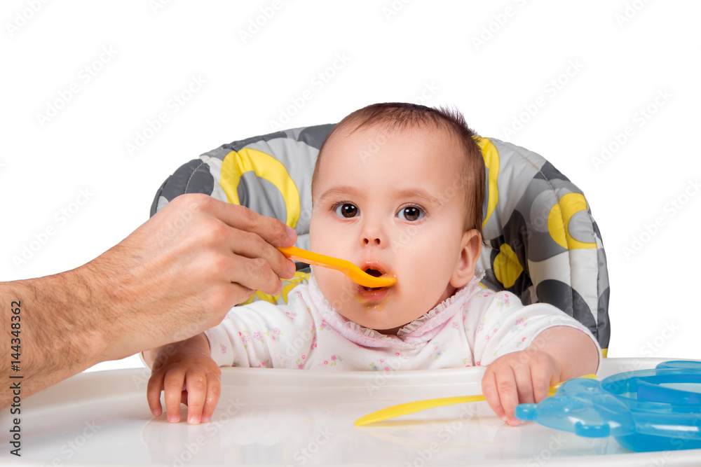 The father feeds with porridge of the one-year-old kid, isolated on the white The father feeds with porridge of the one-year-old kid, isolated on the white