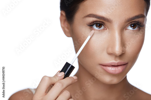 Beautiful Woman Applying Corrector On  Beauty Face. Makeup