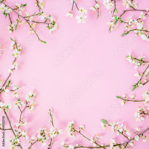 Floral frame made of spring white flowers on pink background. Flat lay, top view. Spring time background.