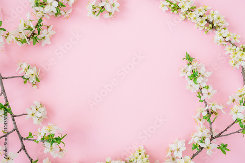 Spring time background. Floral frame of spring white flowers on pink background. Flat lay, top view. © artifirsov
