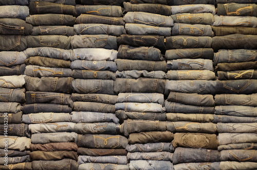 A large number of denim pants in a trendy boutique on the counter. Wall of jeans. The last collection of men's and women's clothing.