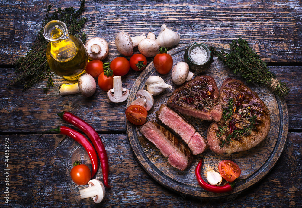  Beef Steak, salt, pepper, garlic, rosemary, mushrooms, olive oil  on the black board, background.