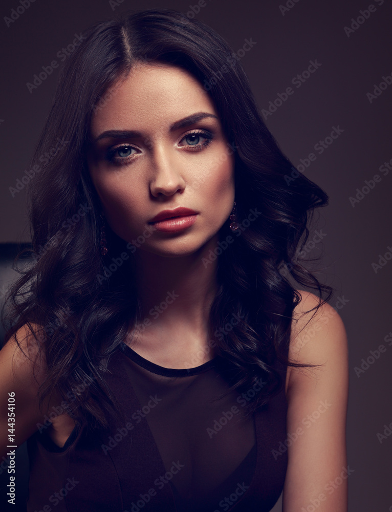 Sexy young makeup model in brown dress and curly hairstyle posing on dark shadow background. Closeup drama art toned portrait. Sexy young makeup model in brown dress and curly hairstyle posing on dark shadow background. Closeup drama art toned portrait.