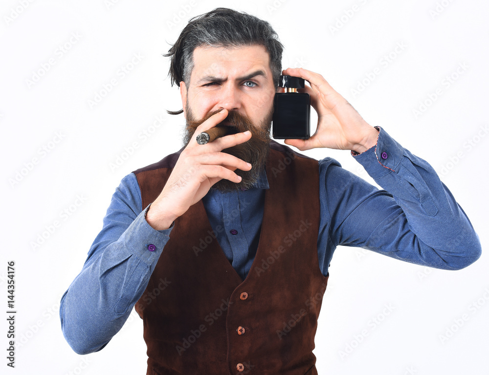 bearded man smoking cigar with serious face, holding perfume bearded man smoking cigar with serious face, holding perfume