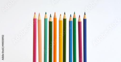 Colored pencils in a row in front of a white background