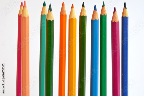 Colored pencils in a row in front of a white background