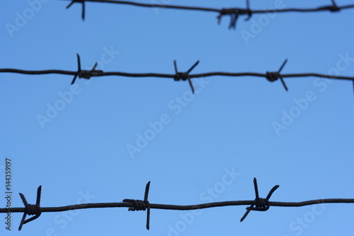 Barbed wire fence against the blue sky