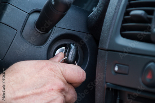 The driver is about to start the car, holds the key in his hand who is in the lock of the car © HappyLenses