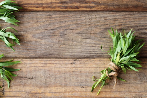 Fototapete Bunch of fresh tarragon on a wooden background with a space for note