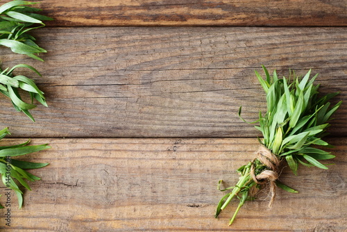 Bunch of fresh tarragon on a wooden background with a space for note photo