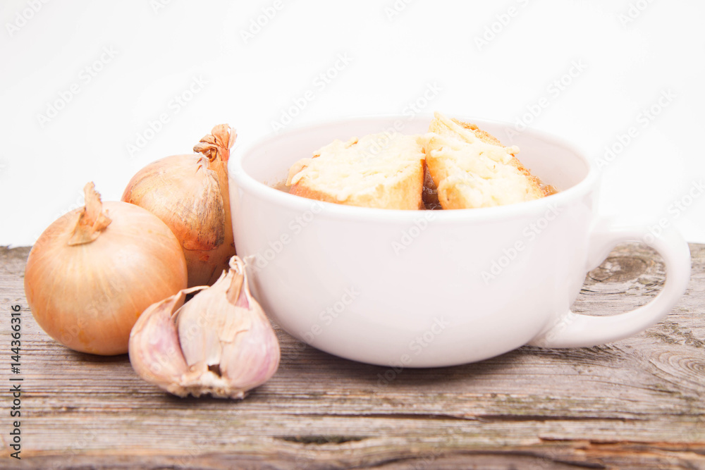 Onion soup with toast on a wooden background with some onions and garlic Onion soup with toast on a wooden background with some onions and garlic