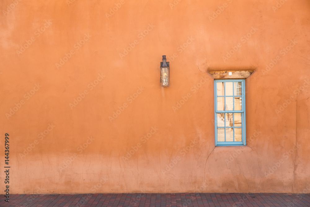 Fototapeta premium pomarańczowa ściana z turkusowym oknem w Santa Fe w Nowym Meksyku